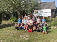 Uczniowie z klas od pierwszej do czwartej pozują do zdjęcia w grupie, część dzieci kuca, część stoi