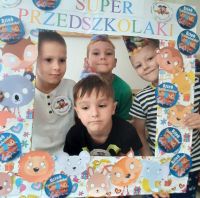 Chłopcy z przedszkola pozują do zdjęcia w przygotowanej ramce z napisem dzień przedszkolaka