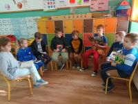 Uczniowie klasy drugiej siedzą na krzesłach w klasie i czytają książki.