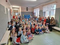 Uczniowie i nauczyciele pozują do zdjęcia grupowego na korytarzu szkolnym