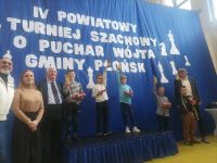 Dzieci na podium odbierający medale za zwycięstwo w turnieju szachowym.