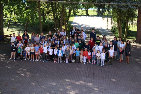 Uczniowie wraz z nauczycielami stoją w grupie  i pozują do zdjęcia
